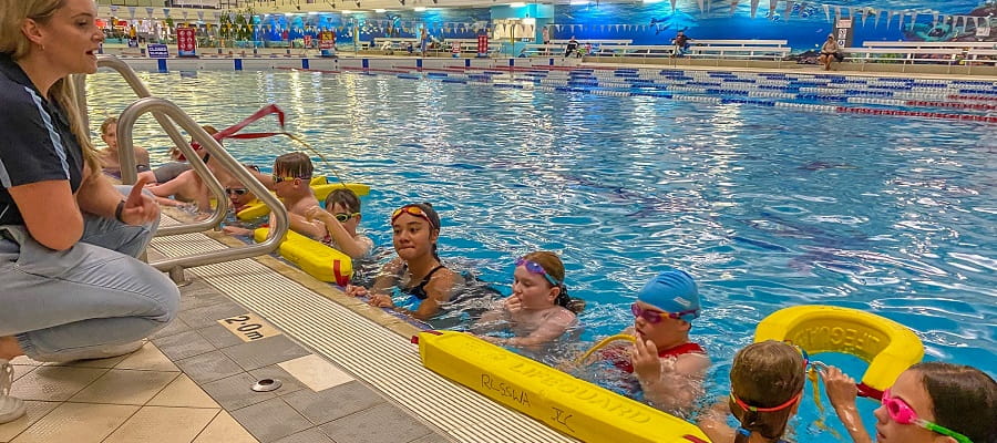 group of children at a swimming lesson holding rescue tubes