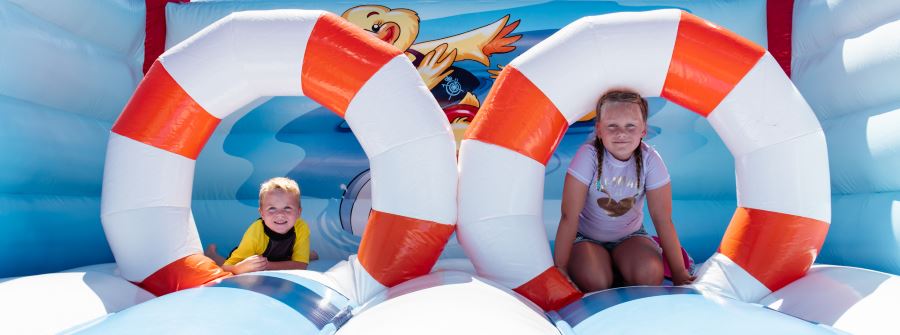 A toddler boy and a young girl sitting under the life rings on the Royal Life Saving WA bouncy castle