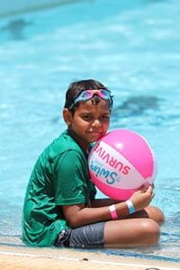 boy holding a Swim and Survive beachball