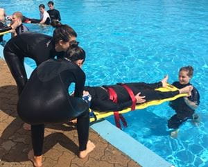 Lifeguards at Adventure World practising spinal board techniques in the pool