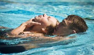 young man performing aquatic rescue of female swimmer