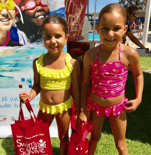 Two little girls in their bathers holding red Swim & Survive Open Day bags