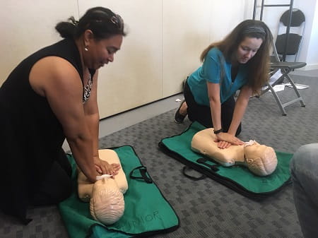 two women practising CPR on manikins
