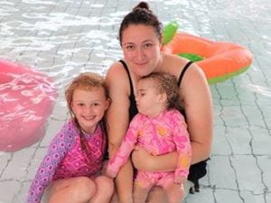 Mother with two daughters in shallow end of pool