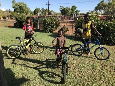 three Aboriginal kids with bicycles they won as prizes