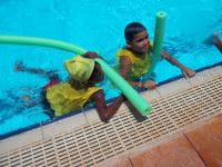Two children in the pool with noodles