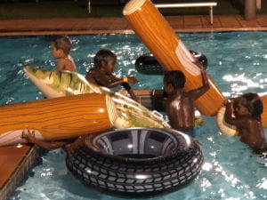 Aboriginal children playing in inflatable toys in the pool