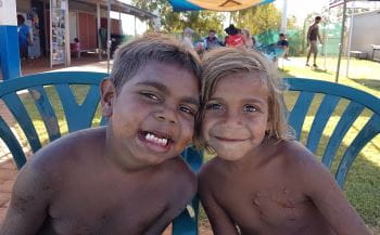Two aboriginal boys sitting on chairs on the grass at the Burringurrah swimming pool