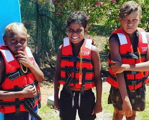 3 Aboriginal boys wearing lifejackets standing by the pool at Burringurrah