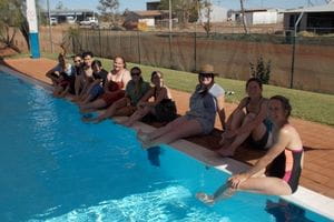 Murdoch University students sitting along the edge of the pool at Burringurrah