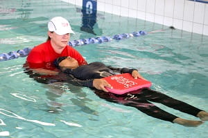 swimming instructor helping multicultural woman learn to float