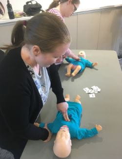 Two woman practising infant CPR on a manikin