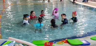 Multicultural children in the water with their swim instructor