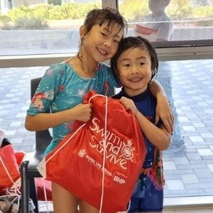 Two girls holding a Swim and Survive bag