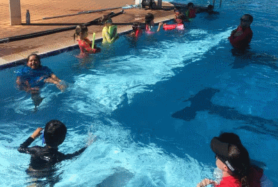 A group of children with two swim instructors in the pool at South Hedland aquatic centre