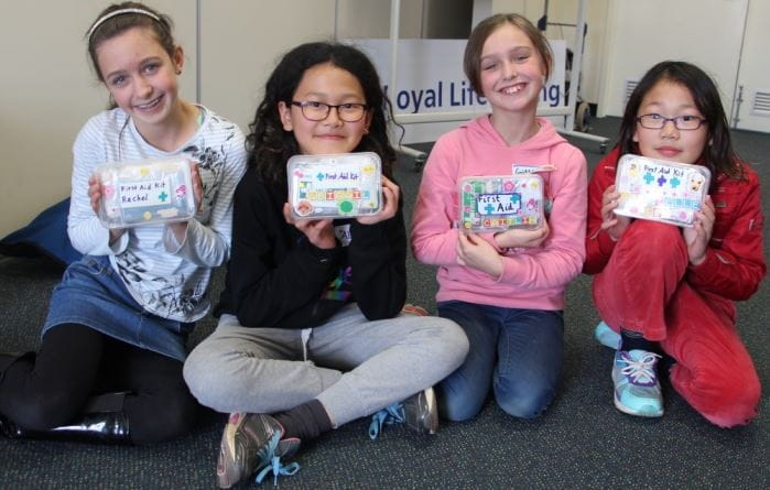 four young girls holding up their first aid kits made at our children's first aid course