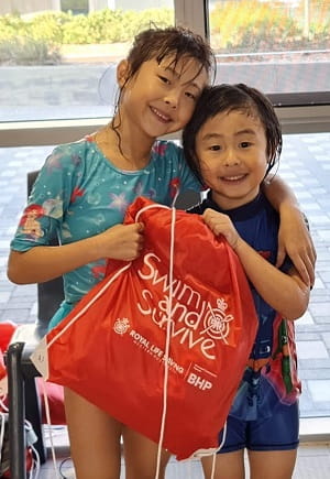 Two multicultural children with a Swim and Survive bag