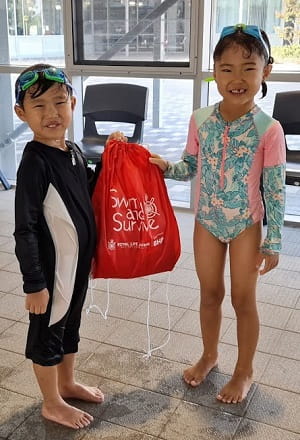 Two multicultural children with a Swim & Survive bag