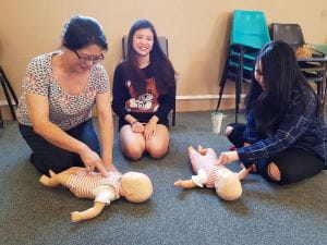 3 Chinese women practising CPR on infant manikins