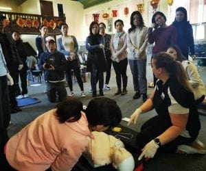 A group of women watching a first aid demonstration with a trainer