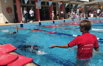 A swim instructor in the water at Churchlands with a student practising backstroke