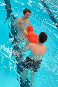 Two Clarkson boys with a lifesaving manikin in the pool