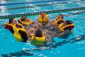 Clarkson students wearing lifejackets in the pool with their Chaplain