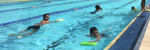 Aboriginal boys swimming with kick boards in a pool