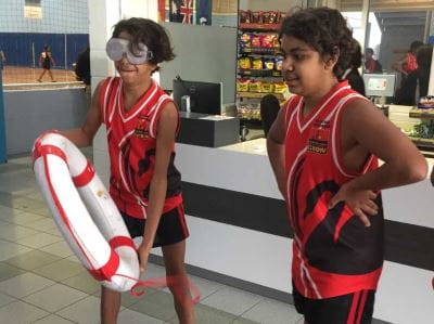two Aboriginal boys with one wearing beer goggles and holding a lifesaving ring