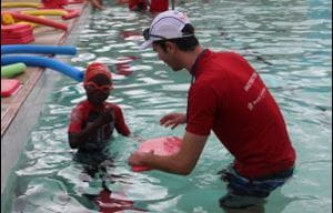 A boy smiling at the camera with his swim instructor