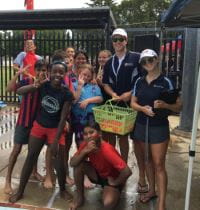 Kids and instructors with happy faces standing by the side of the pool