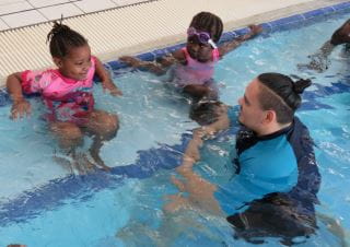 two young girls in the pool with their instructor at Balga