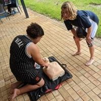 Two boys practising CPR on a manikin