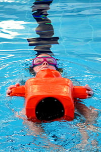 child swimming with orange pool manikin