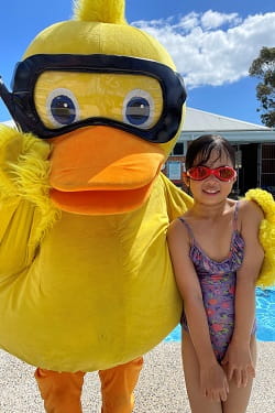 young swimmer with Dippy Duck next to a pool