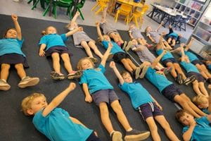 Children laying on the floor waving their arm in the air
