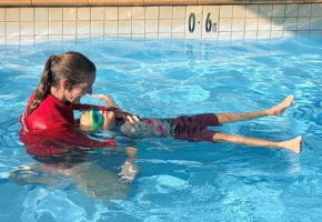 Swim instructor with a young boy practising a back float