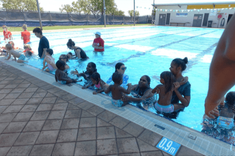 Group of Aboriginal women and their babies in a swimming pool at Fitzroy Crossing