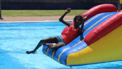 An aboriginal boy sliding off the pool inflatable at Fitzroy