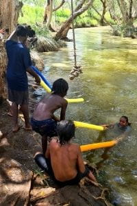 Aboriginal kids practising rescues with pool noodles in a river