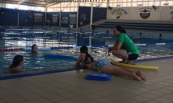 Girls from Geraldton girls academy in the pool while one lays on the edge to rescue them, with an instructor nearby