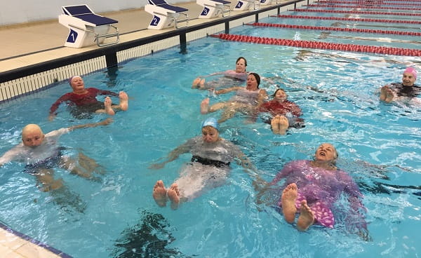nine senior women practising survival skills in a pool