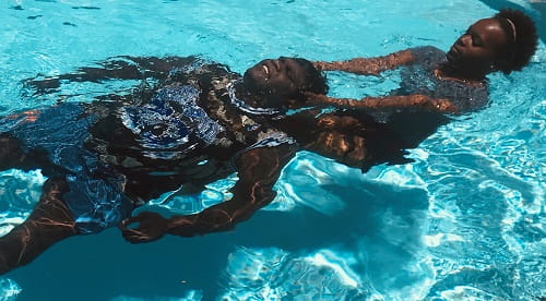 Aboriginal woman performing aquatic rescue on Aboriginal man in swimming pool
