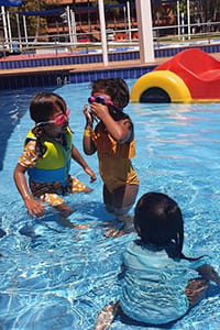Three toddlers playing in a swimming pool