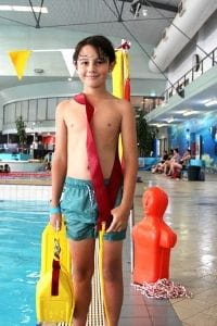 A young boy with a lifeguard rescue tube by the pool