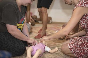 Two women practising infant CPR on a manikin