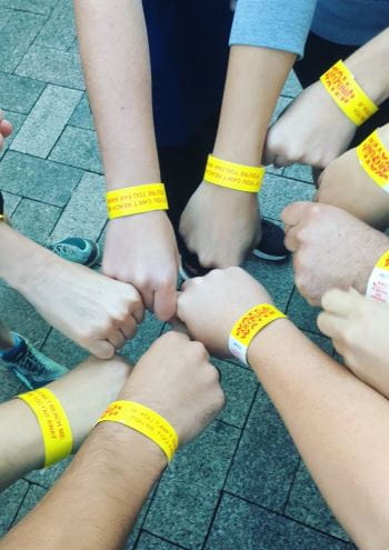 Team members holding their hands in a circle to show their Watch Around Water wrist bands