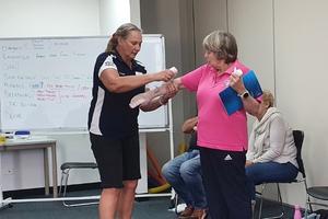 Trainer Cathie Calleja bandaging a woman's arm during a first aid refresher course