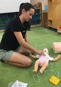young woman practising CPR on an infant manikin