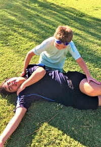 young boy practises putting someone in recovery position